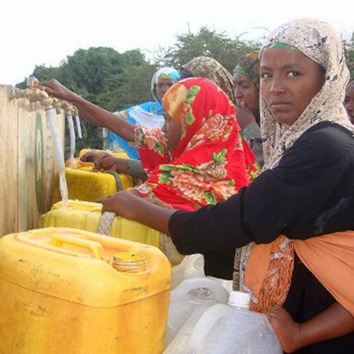 Woman getting water from a shared well.