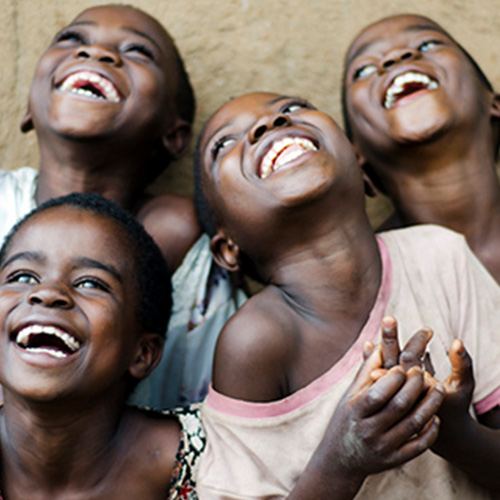 4 smiling young children, looking up